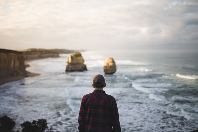 Rear view of man standing in sea against sky