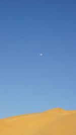 Scenic view of desert against clear blue sky