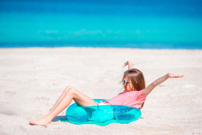 Girl sitting on inflatable ring at beach