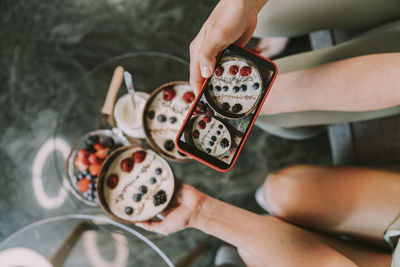 Girl photographing fruit bowls through smart phone