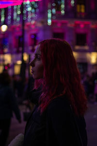 Rear view of woman looking at illuminated city at night