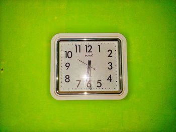 Close-up of clock in a green background showing time 6.30 .