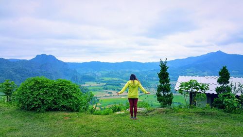 Rear view of woman looking at mountains against sky