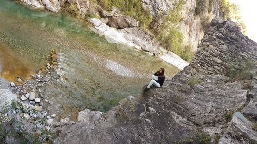 Full length of young woman sitting by river