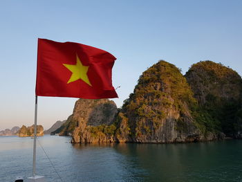 Red rock in sea against clear sky