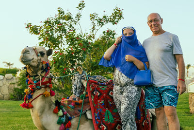 Portrait of man with camel on field