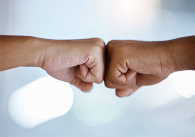 Cropped hand of woman holding hands against white background