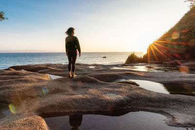 Rear view of man standing on beach during sunset