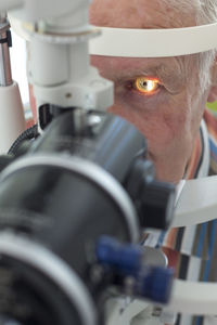 Close-up of man looking through optometrist phoropter