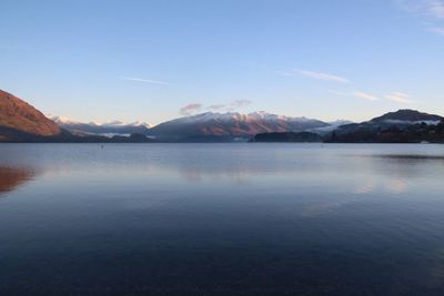 Scenic view of lake by mountains against sky