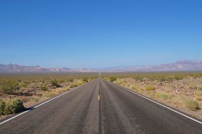 Road leading towards mountains against sky