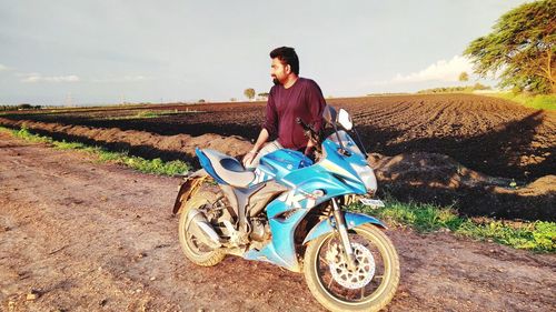 Portrait of man sitting on land against sky