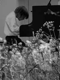 Side view of man standing by flowering plants