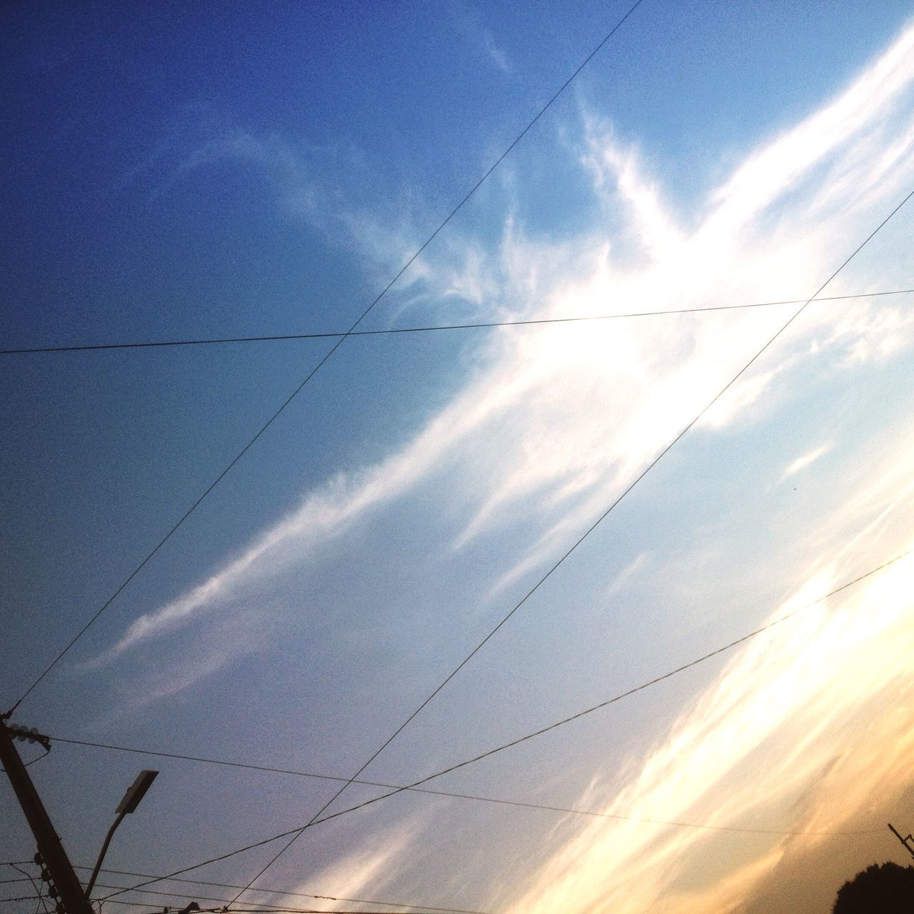 sky, low angle view, cloud - sky, power line, blue, scenics, tranquility, beauty in nature, cloud, nature, tranquil scene, cloudy, electricity, vapor trail, silhouette, cable, connection, outdoors, no people, electricity pylon