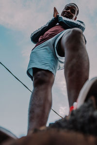 Low section of man with rope against sky