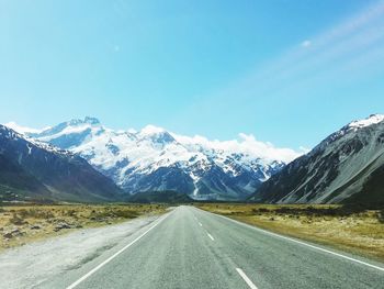 Road amidst snowcapped mountains against sky