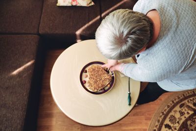 High angle view of man holding coffee cup on table