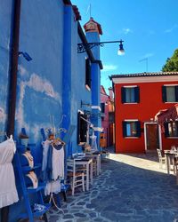 Street by buildings against blue sky in burano, venice