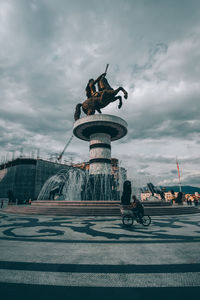 Statue in city against cloudy sky
