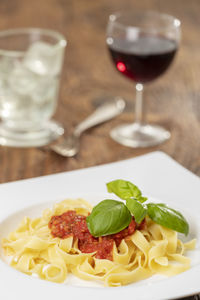 Close-up of pasta served in plate with wine on table