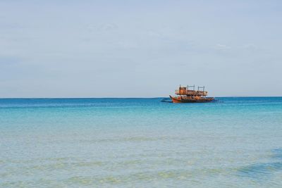 Boat sailing in sea against sky on sunny day