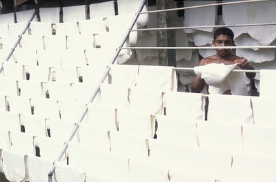 Man drying white fabric on rod at industry