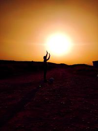 Silhouette man standing on field against sky during sunset