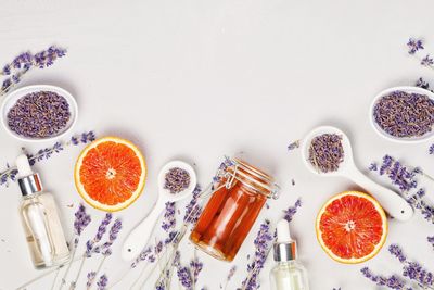 Lavender flowers and halved blood orange with spoons over white background