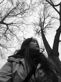 Low angle view of woman wearing warm clothing while standing against trees