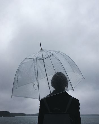 REAR VIEW OF MAN AGAINST SEA