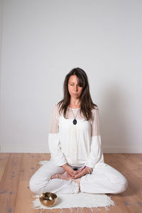 Young woman using phone while sitting on wooden floor