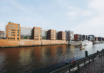 Boats moored at harbor against buildings in city