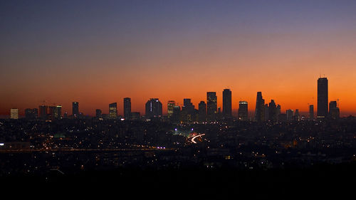 Illuminated cityscape against sky during sunset