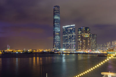 Illuminated modern buildings in city against sky at night