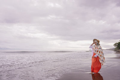 Woman standing at beach against sky