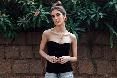 Portrait of young woman standing against brick wall