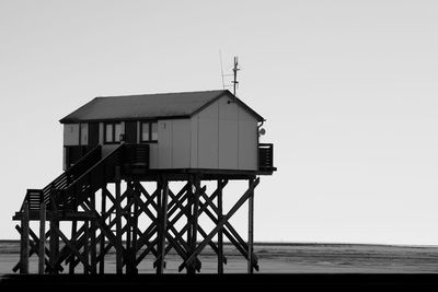 Hut on beach by sea against clear sky