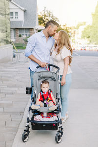 Caucasian mother and father walking with baby daughter in stroller. family strolling together 