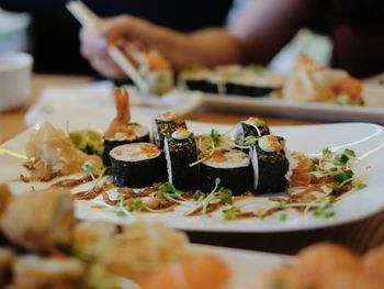 Cropped hand having sushi at table