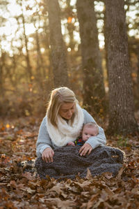 Mother and daughter on tree in forest during autumn