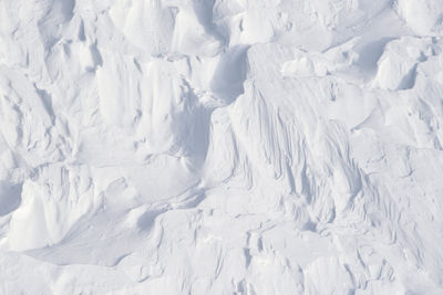 Winds have carved into this powder alpine snow. background bright white abstract texture