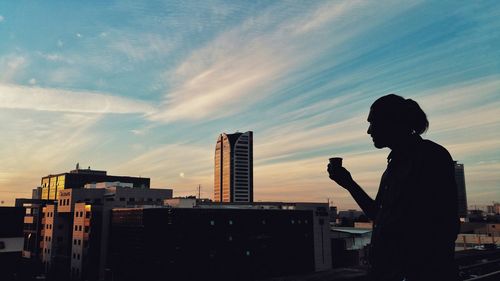 Silhouette of man and cityscape against sky