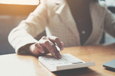 Midsection of man using mobile phone while sitting on table