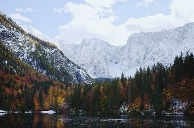 Scenic view of the snow covered mountains against the autumn forest and italian lake.