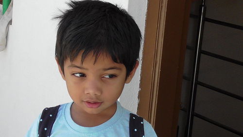 Close-up of thoughtful boy standing against wall