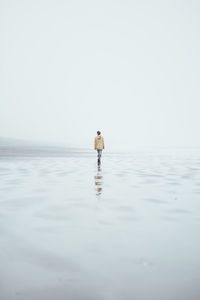 Rear view of man in sea against clear sky