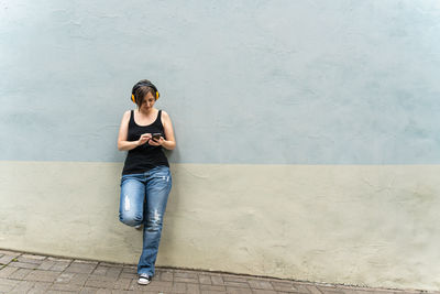 Portrait of young woman standing against wall