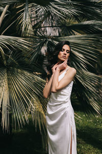 Portrait of woman standing by palm tree