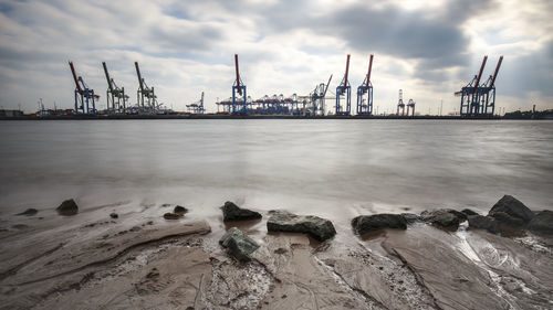 Cranes at commercial dock against sky