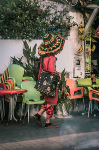 Rear view of woman standing by chairs at table